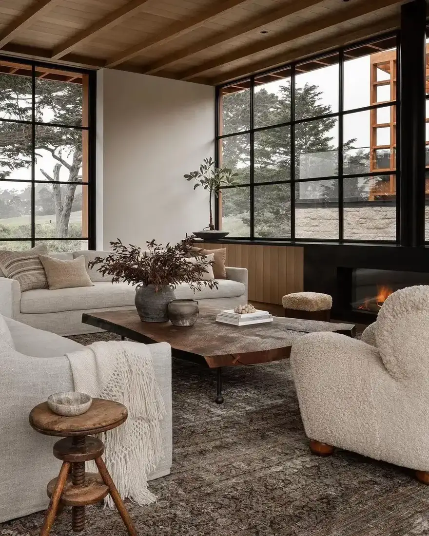 Glass corner room with black frames, fire, live edge table and boucle chairs