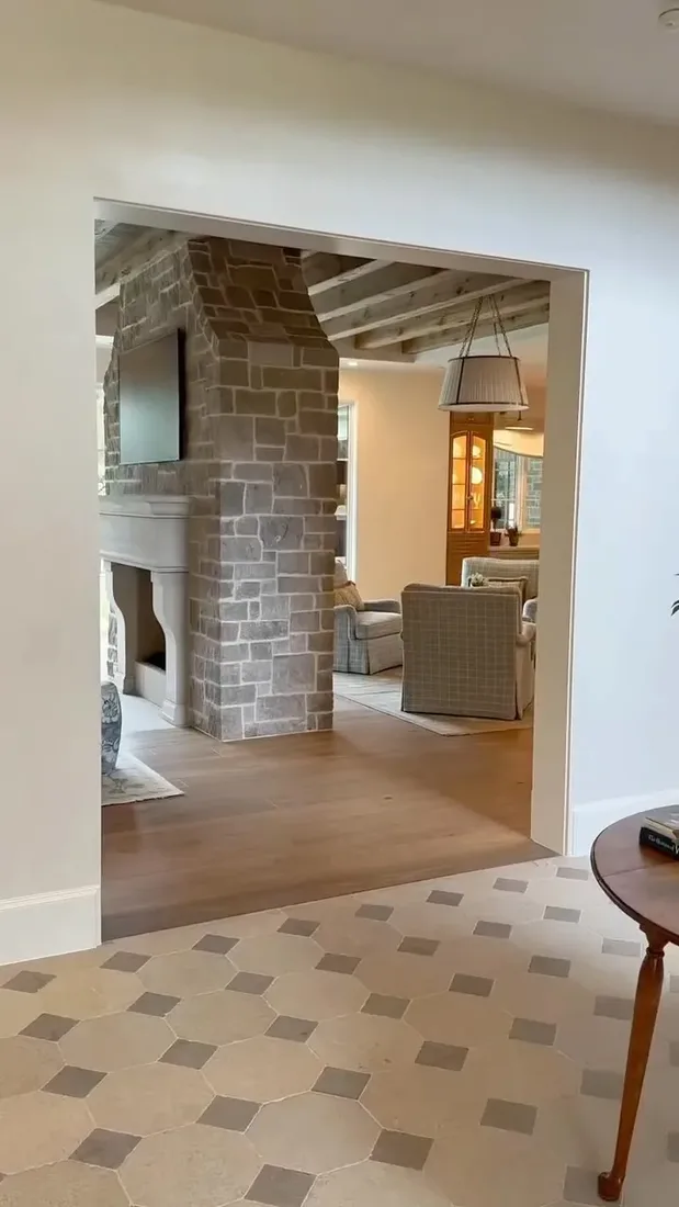 Grey sawn stone chimney breast seen through a doorway, pale surround, television mounted at the side, oak floors