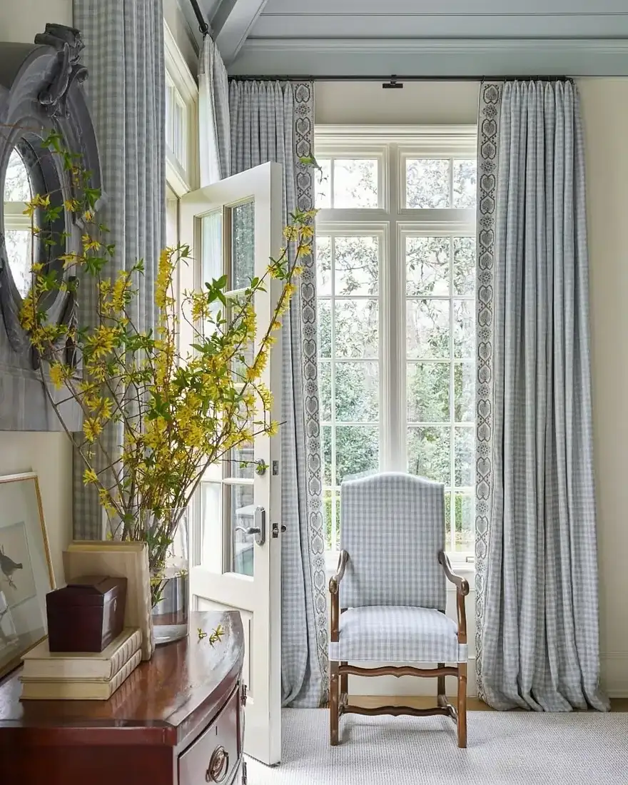 Gingham curtains with applied border tape on the leading edge, beside a matching chair