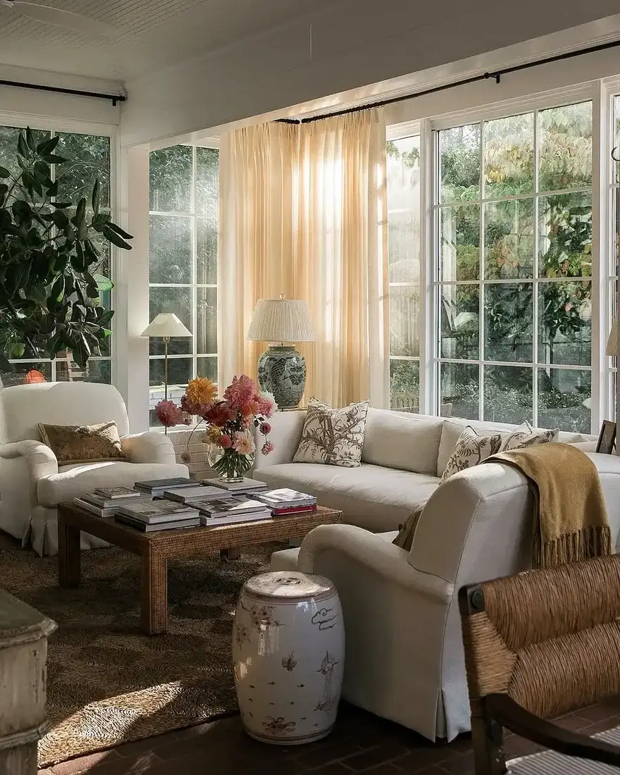 Slipcovered sitting room with full height sheers, rattan table, and garden stool
