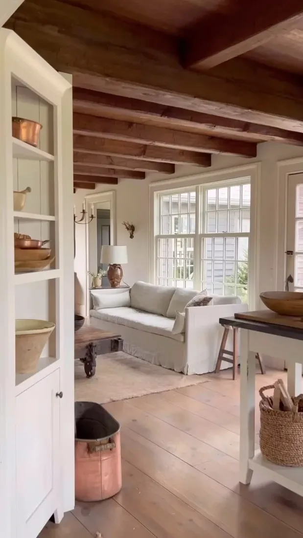 Vaulted sitting room with pale ceiling between dark beams and soft neutral textiles
