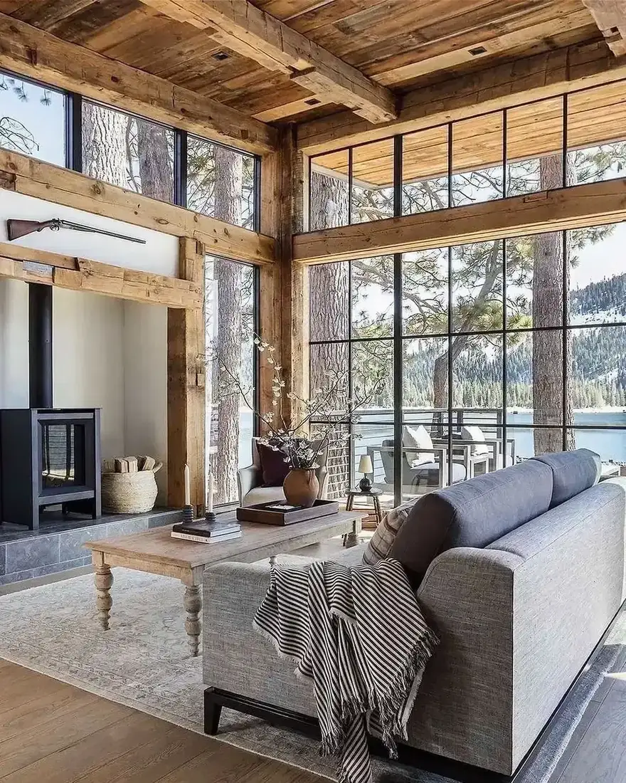 Cabin sitting room with stone fireplace, dark beams and a restrained neutral palette