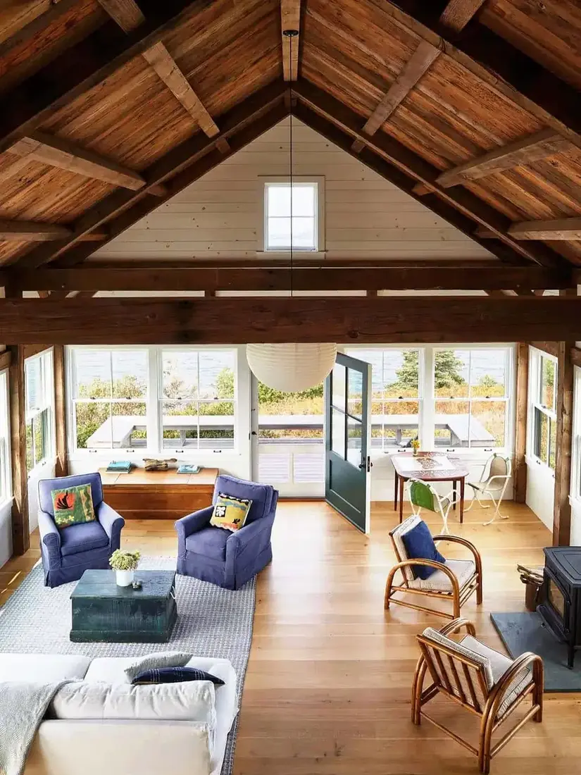 Sitting room with an oak truss ceiling, stone hearth and dusty blue armchairs