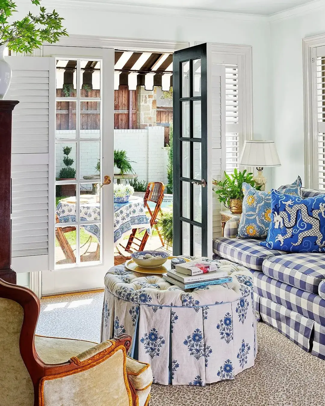 White louvred shutters folded flat beside open French doors in a blue and white country living room