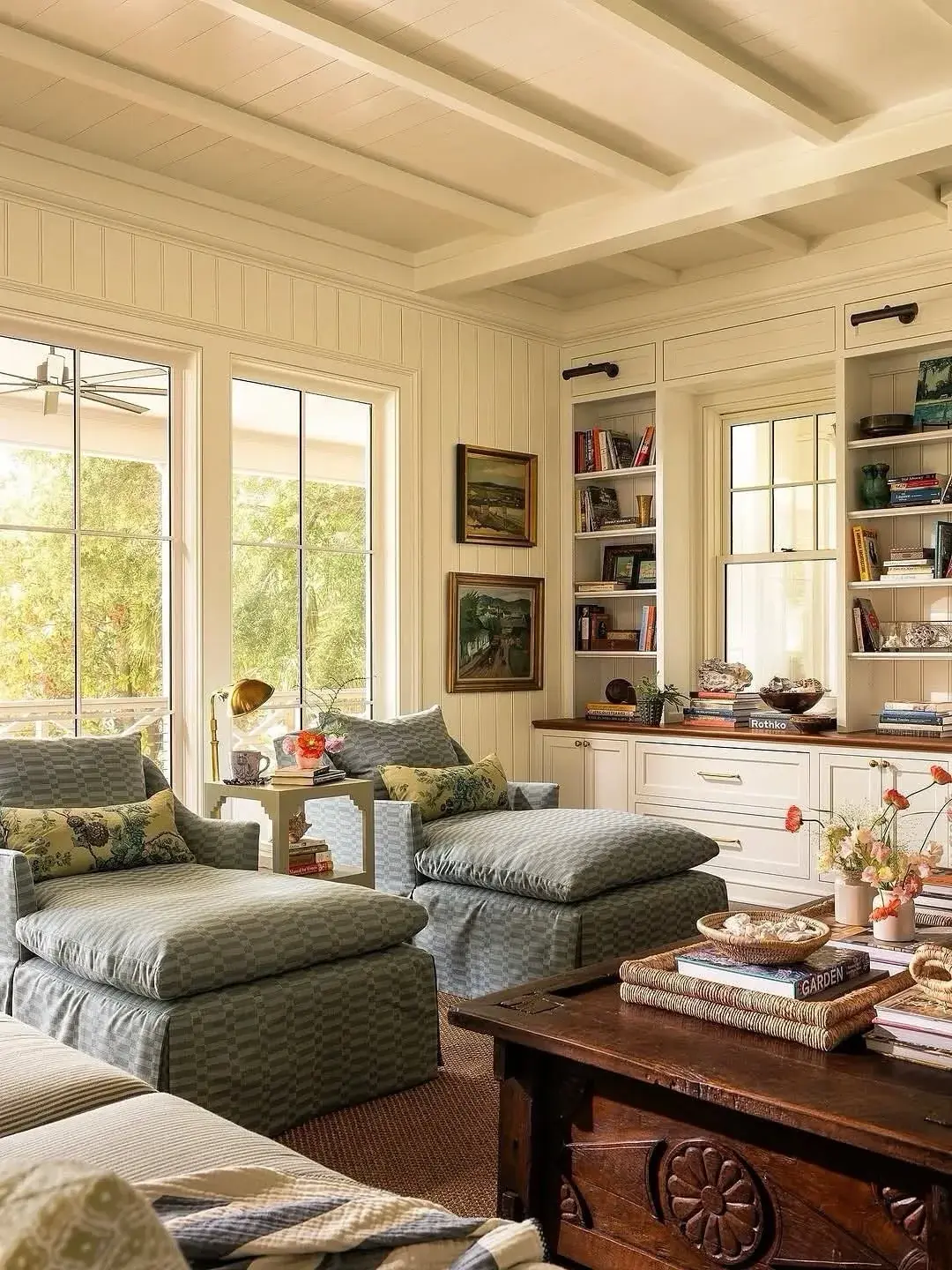 Two grey-blue check chaise longues facing each other in a cream panelled room with built-in bookshelves
