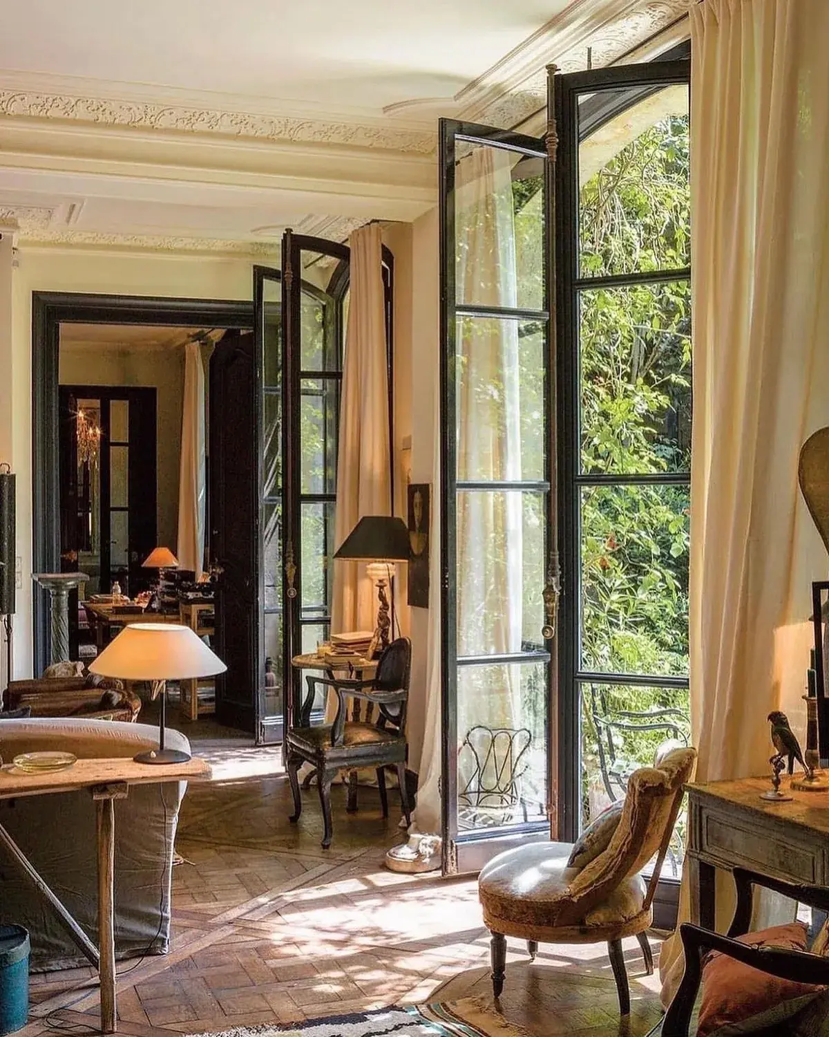Tall black steel French windows with cream curtains and white voile in a Paris apartment