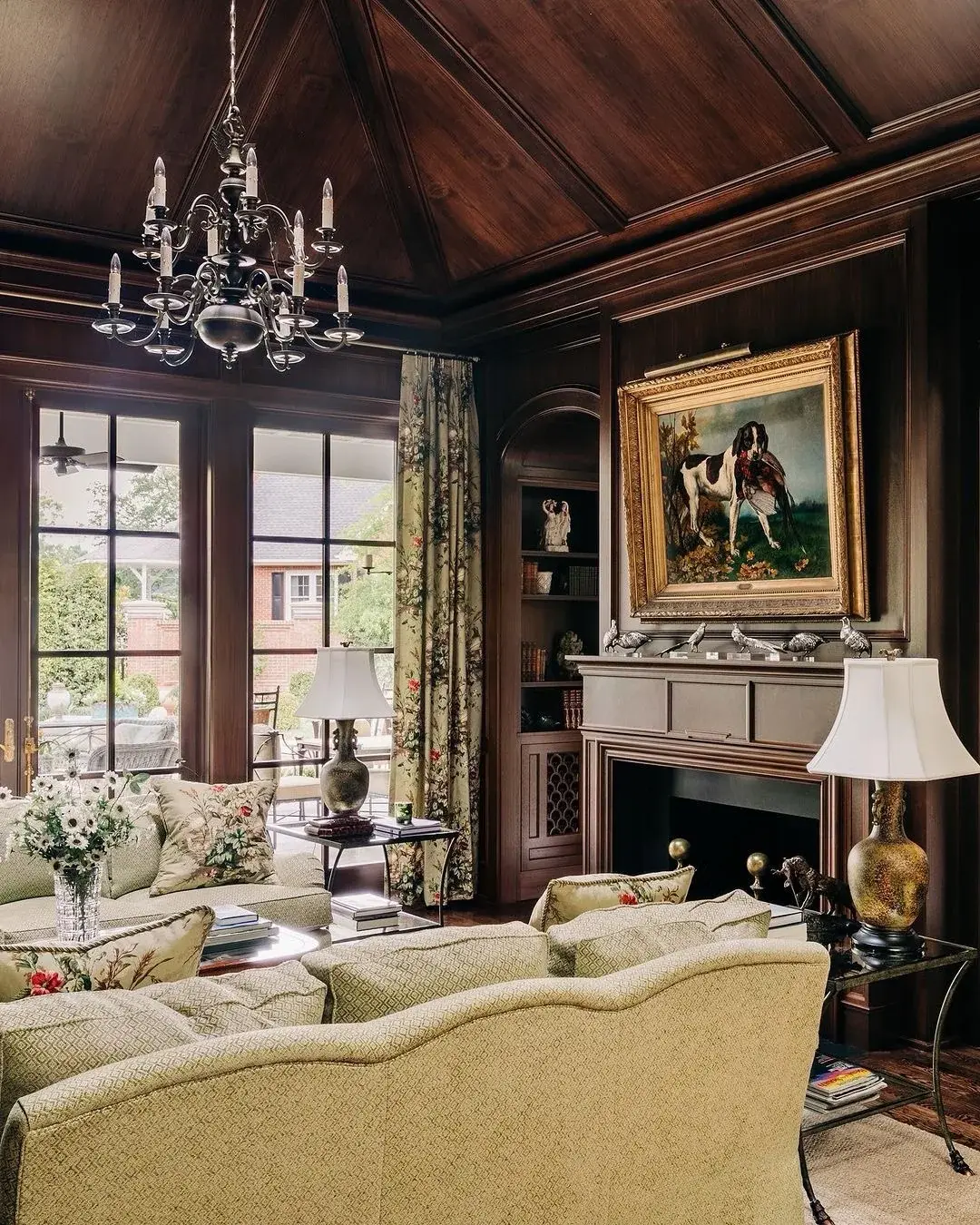 Dark stained wood panelled room with a coffered ceiling, a dog painting and cream floral curtains