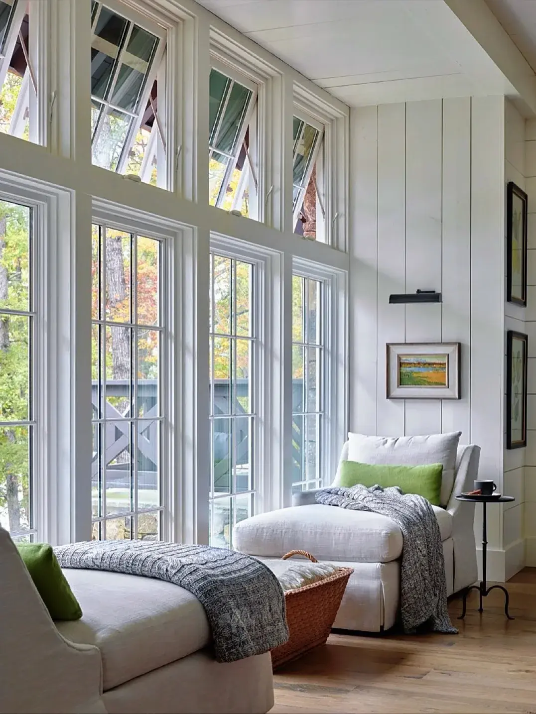 Sunlit chaises with grey throws beside garden windows