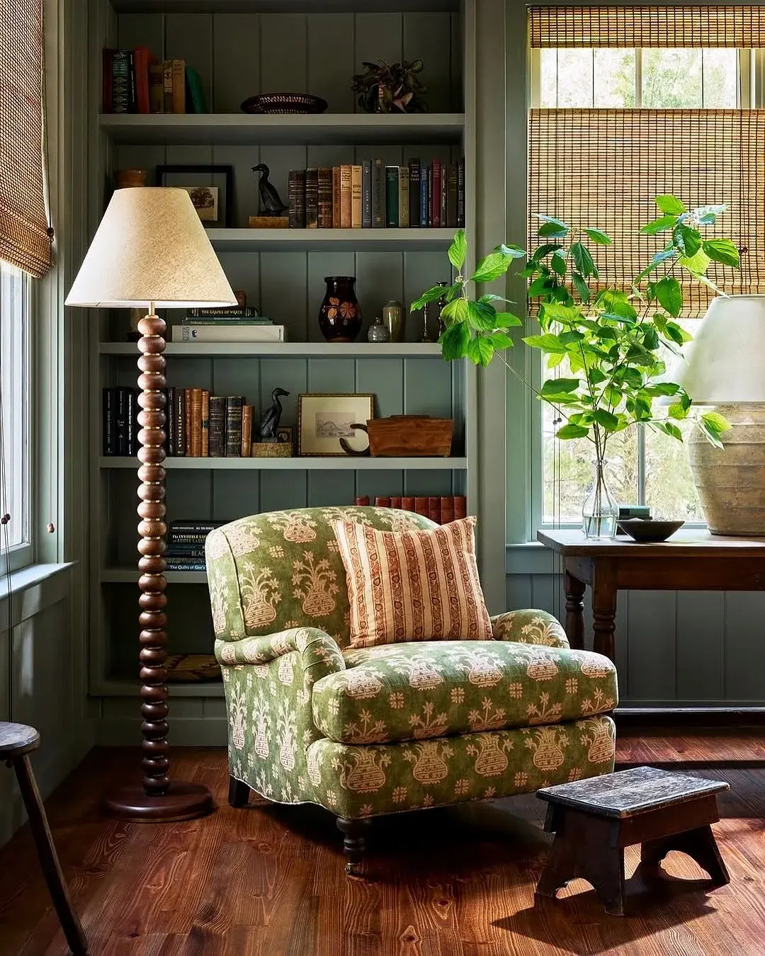 Green floral armchair between sage shelves with bobbin lamp
