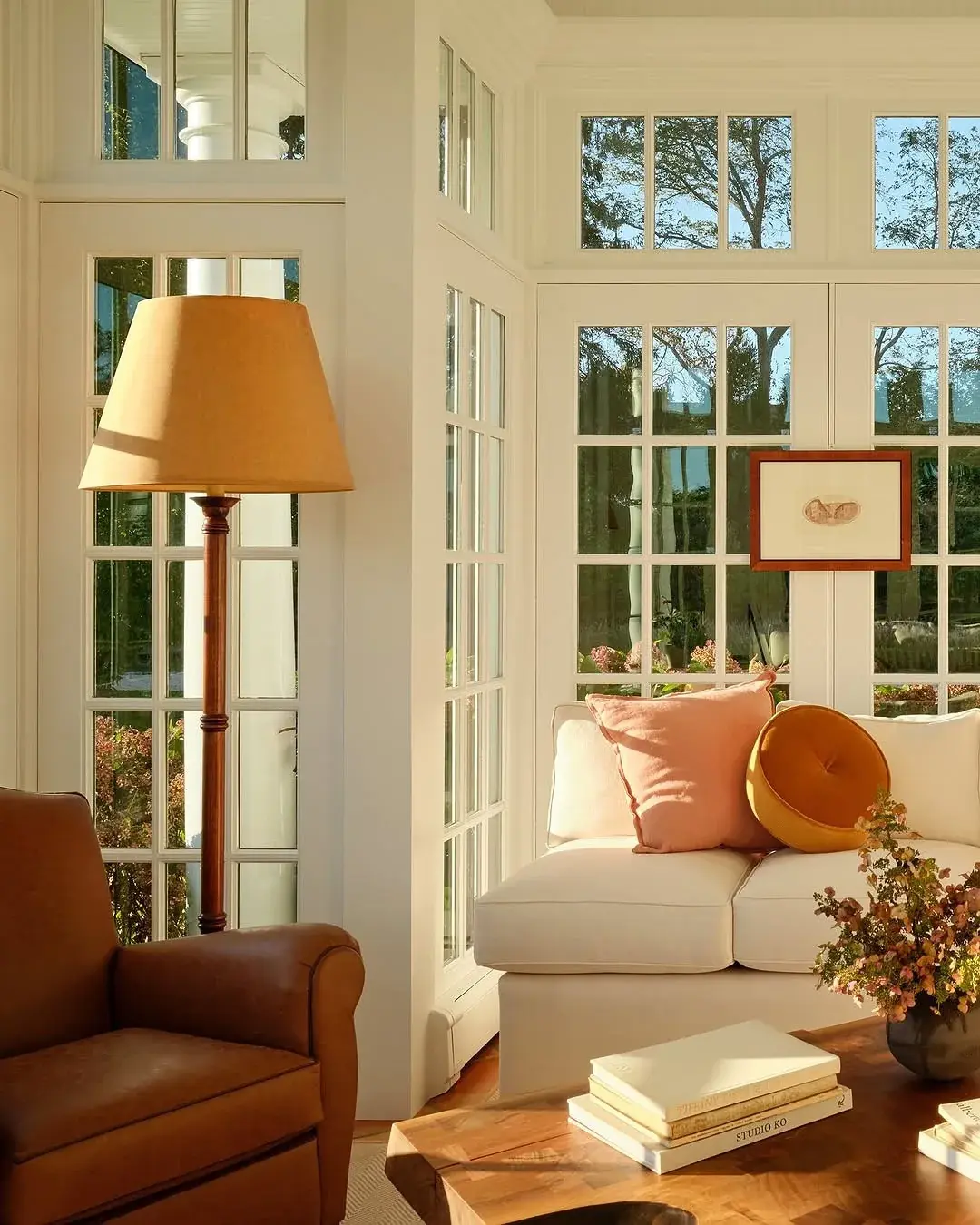 White window seat with pink cushions beside leather chair