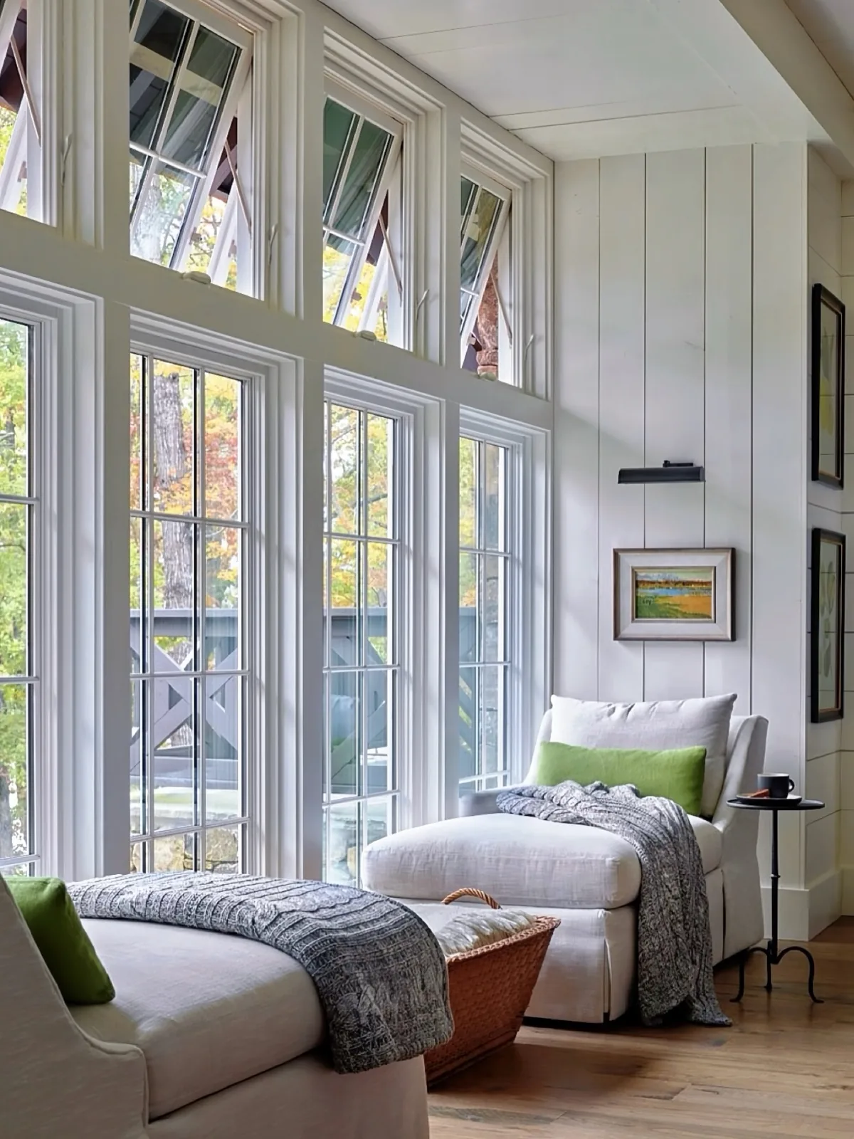 White chaises with green cushions under tall windows