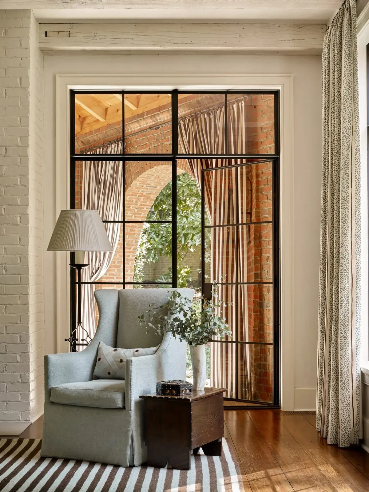 Pale blue wing chair before black steel windows