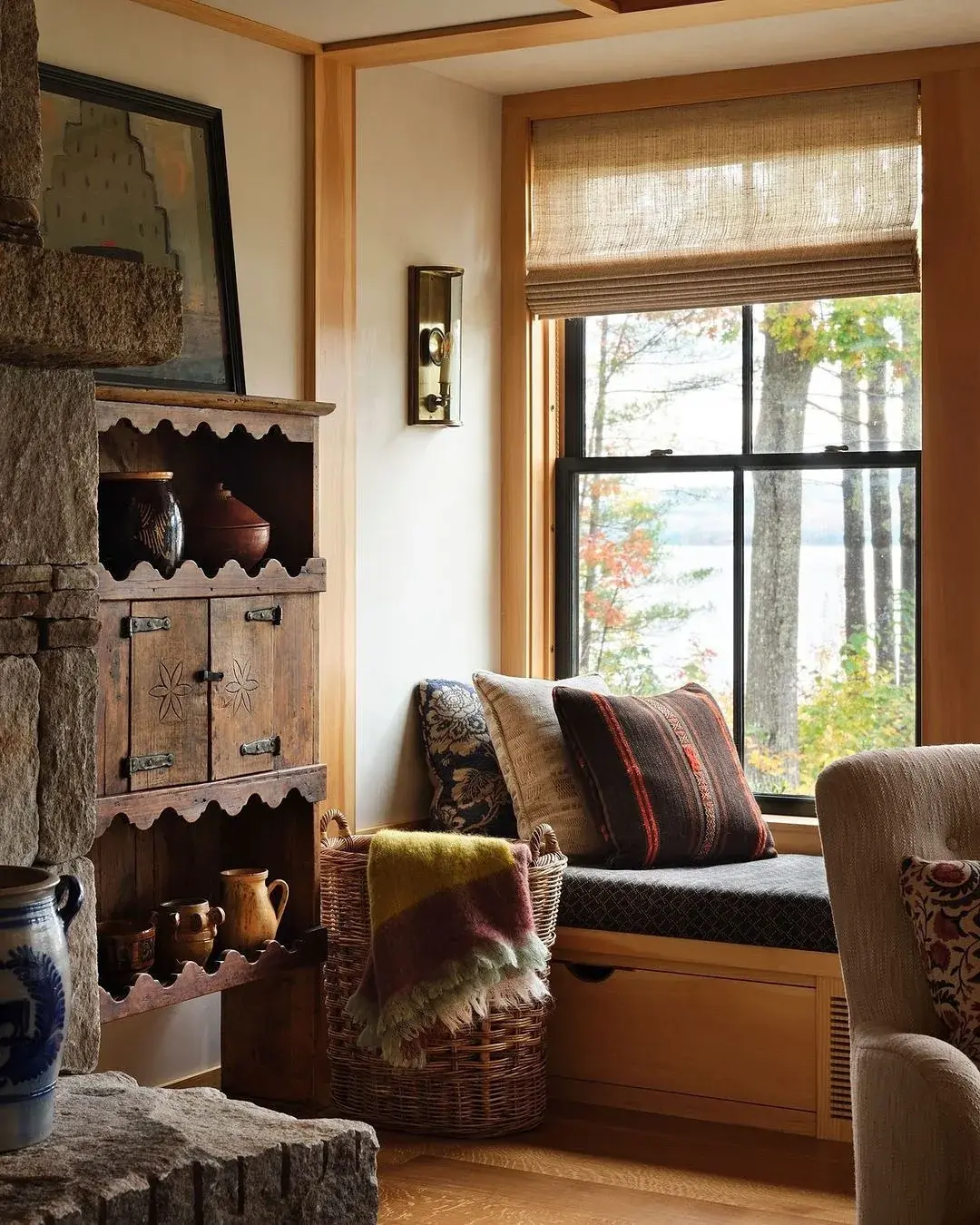 Pine window seat with patterned cushions beside antique cupboard