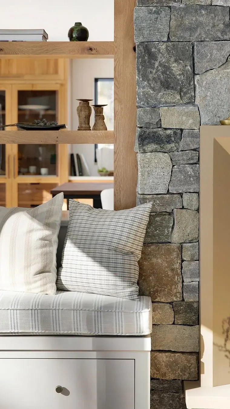 Striped cushion on white seat against stone wall