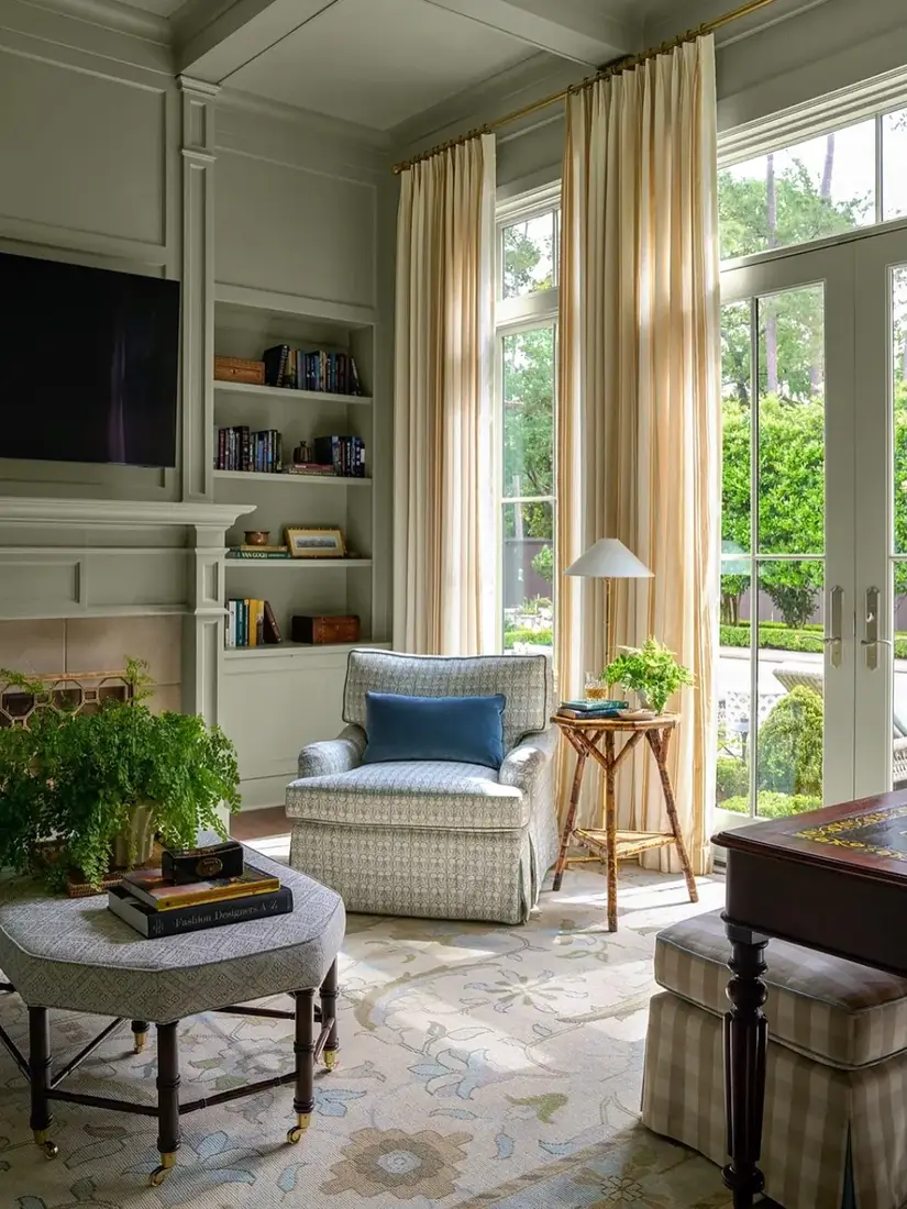 Sage green built-in bookcases in a bright sitting room with an arched doorway